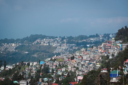 Free A picturesque view of a vibrant hill town in India with colorful buildings against a mountainous backdrop. Stock Photo