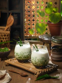 Delicious traditional Indonesian cendol dessert served in bamboo cups amidst a rustic wooden backdrop.