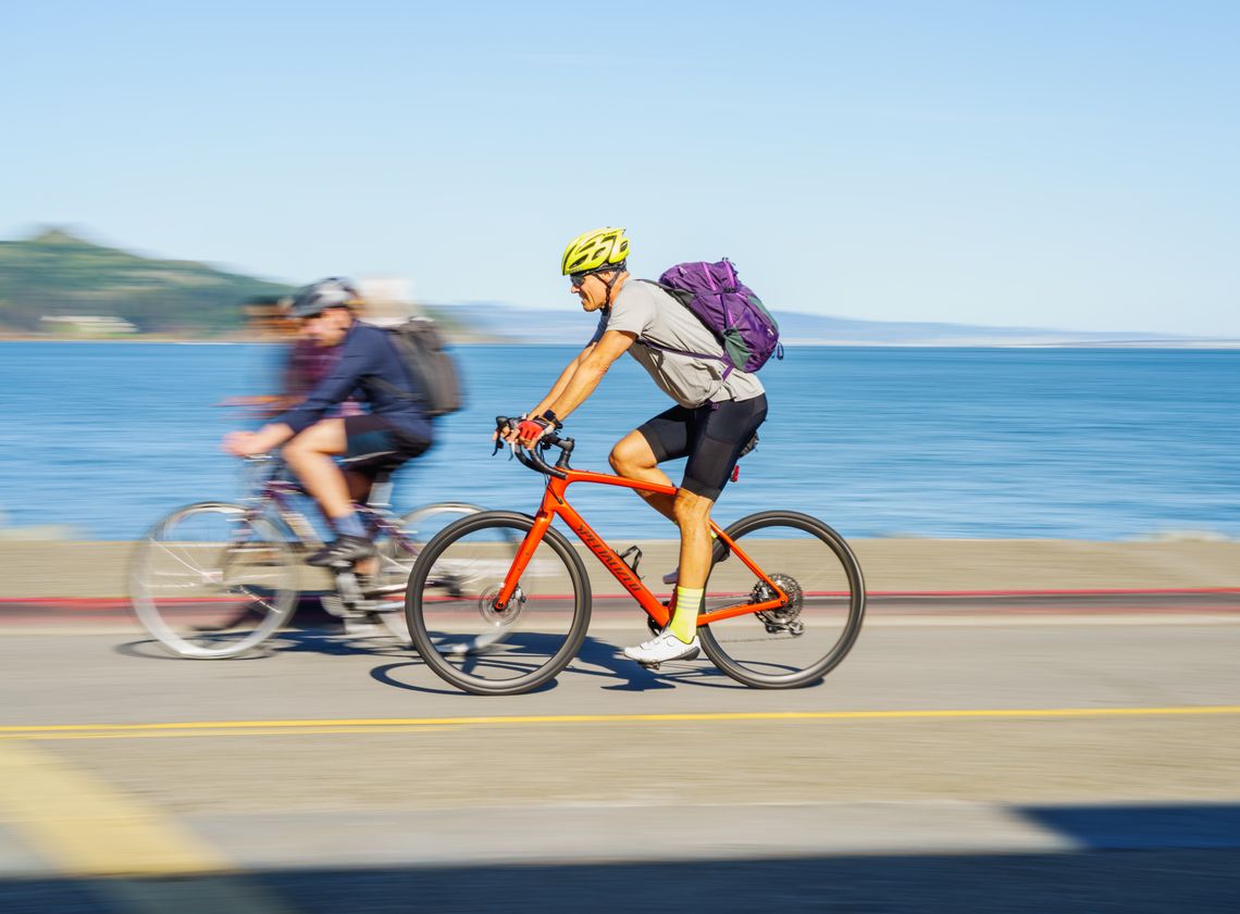 Urban cyclist wearing a helmet and backpack while riding a road bicycle