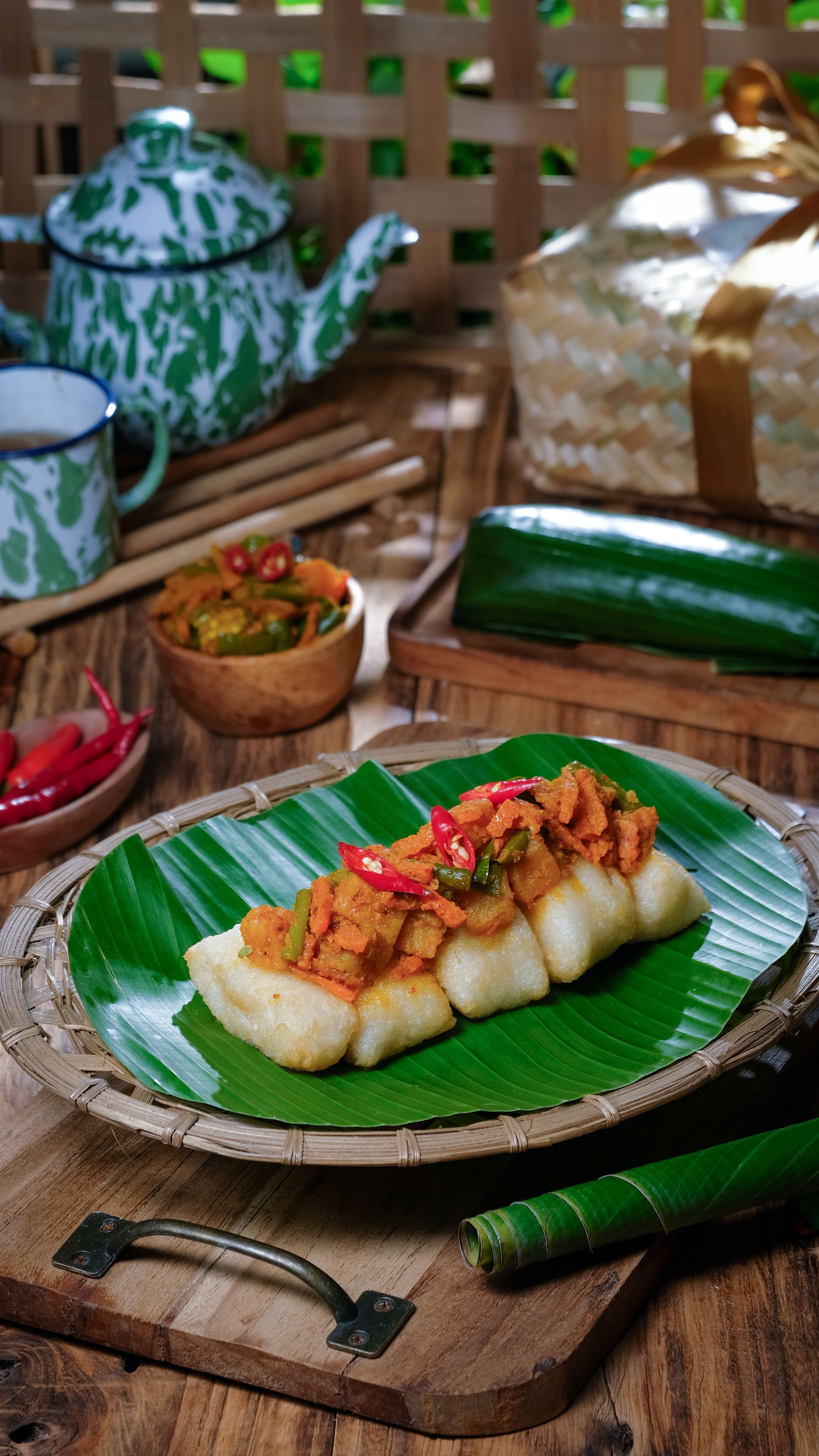 A traditional Indonesian dish, Lontong Sayur, served on a banana leaf with vibrant chilies.