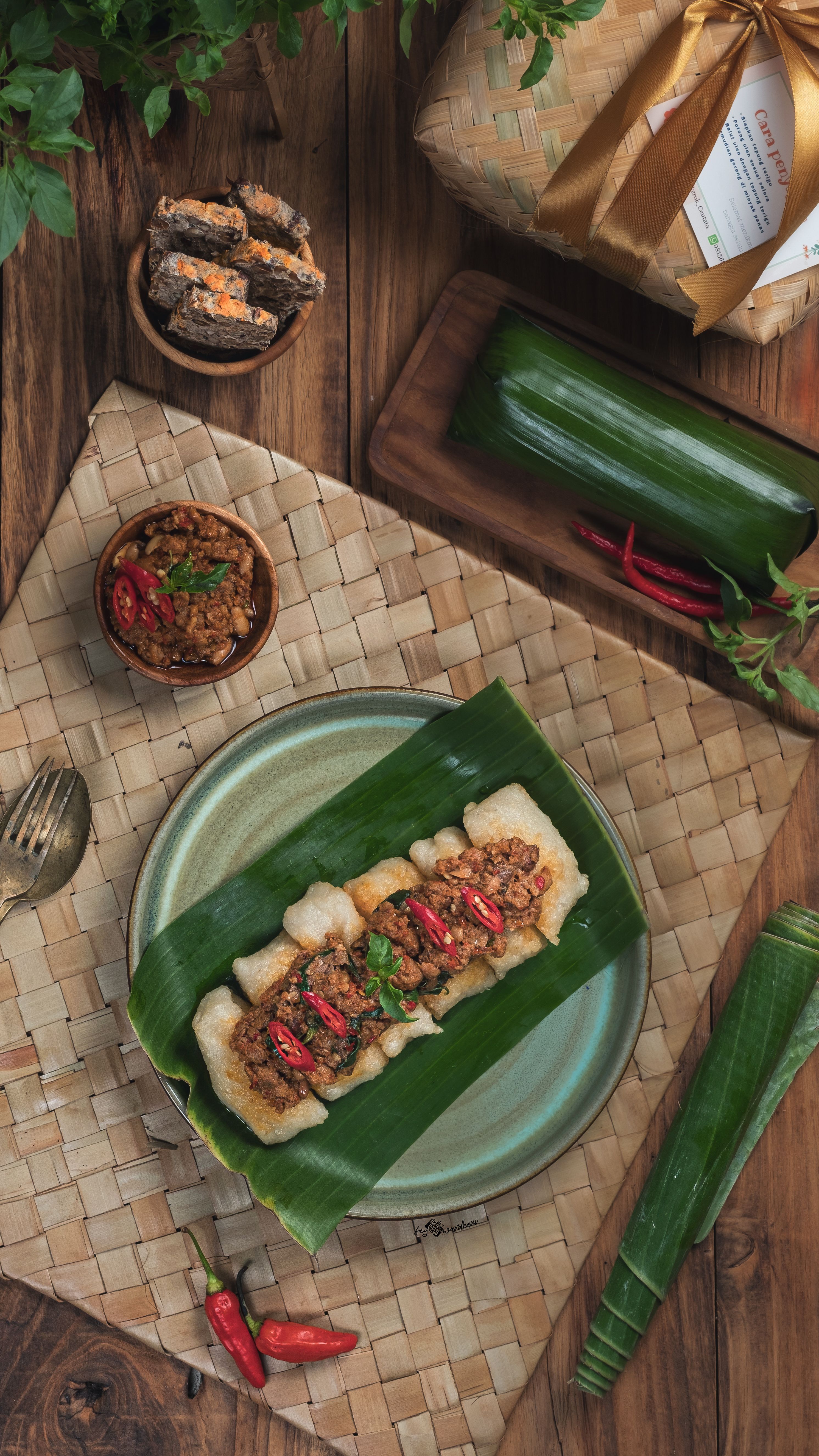 Traditional Indonesian dish served on banana leaf with sambal, beautifully presented on woven mat.