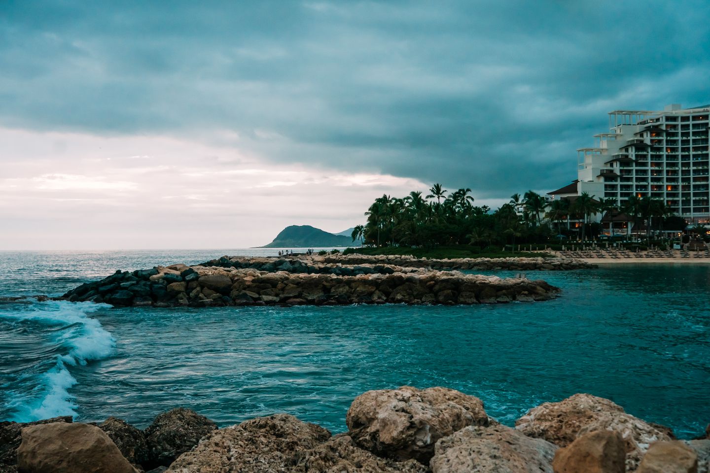The Ko Olina coastline on Oʻahu, resort buildings above a rocky shore under heavy sky
