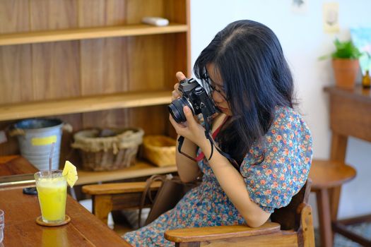 A young woman enjoying photography in a cozy café setting in Hue, Vietnam.