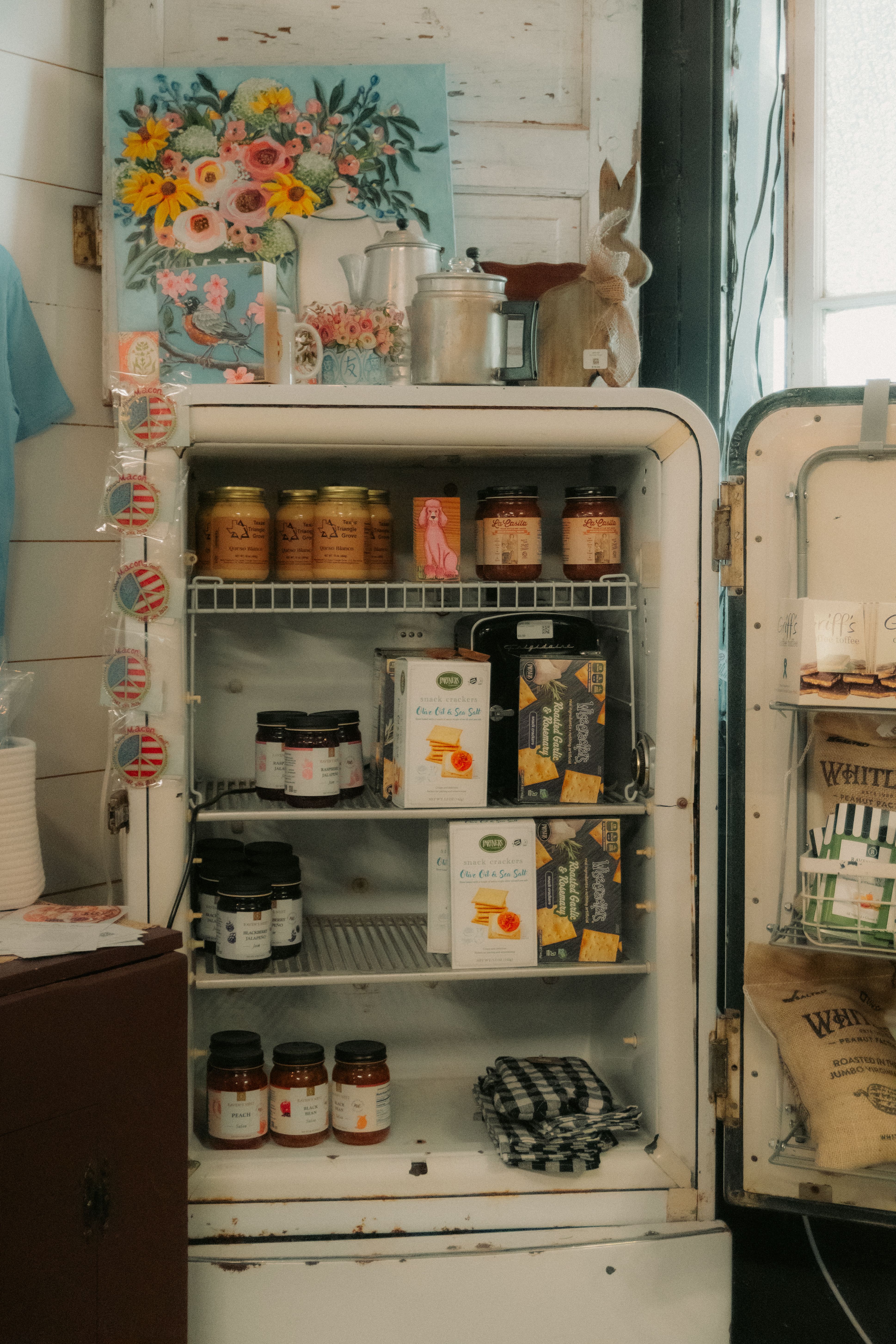 A vintage refrigerator displaying jars and artwork in a cozy indoor setting, creating a nostalgic ambiance.