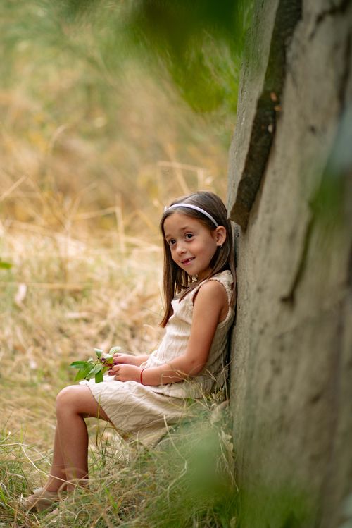 Free Charming girl sitting by a tree outdoors in autumn, smiling gently. Stock Photo
