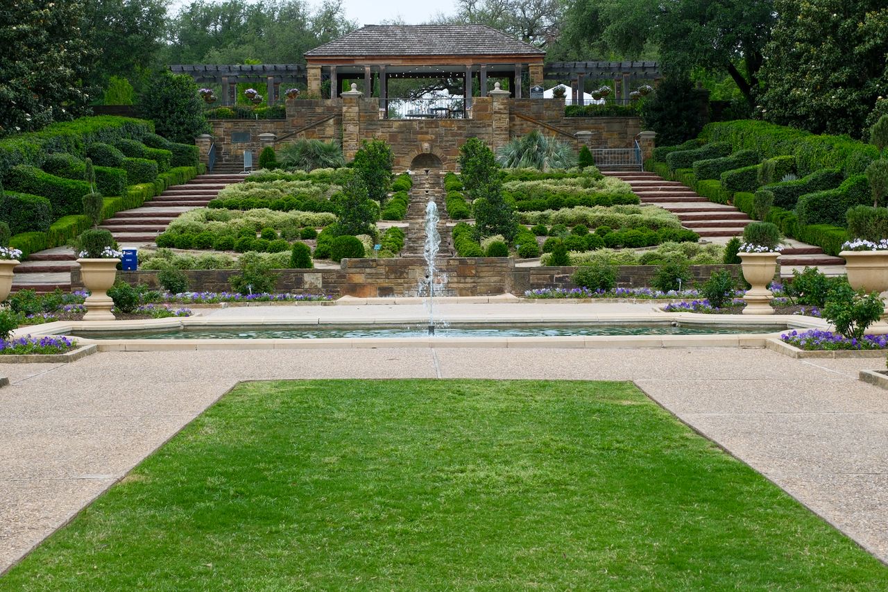Terraced garden with stone retaining walls, lawn panel and fountain on a slope