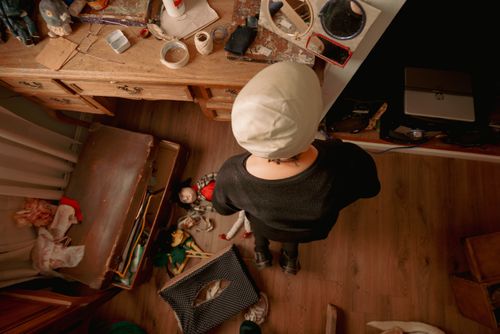 Free Top view of a creative workspace with a person overlooking dolls and craft materials. Stock Photo