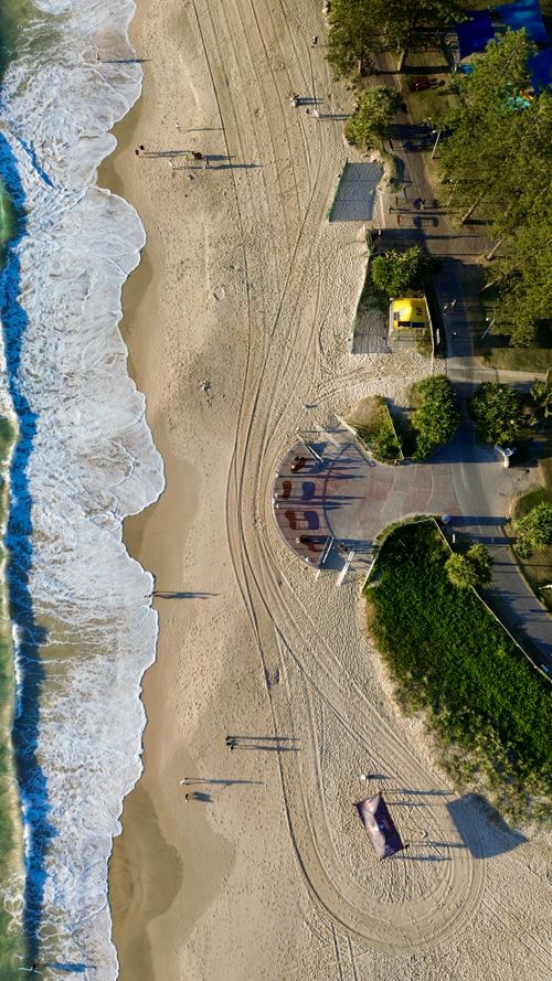 Free Aerial shot of a coastal beach with ocean waves and walking paths in Gold Coast. Stock Photo