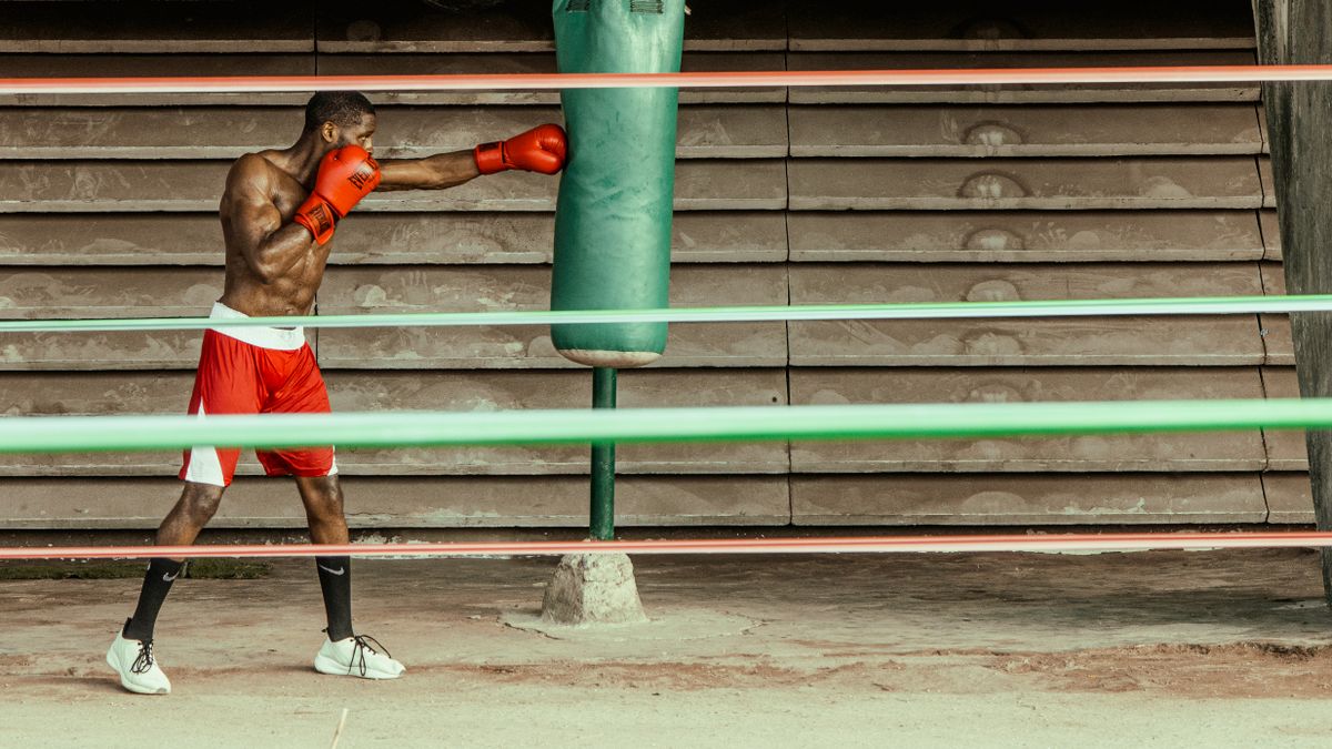 Boxer training with a heavy punching bag in a gym