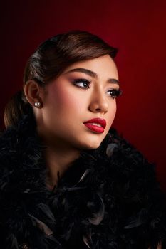 Captivating portrait of a woman with striking makeup against a rich red background.