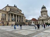 Tourists explore Gendarmenmarkt Square in Berlin with the Concert Hall and French Cathedral.
