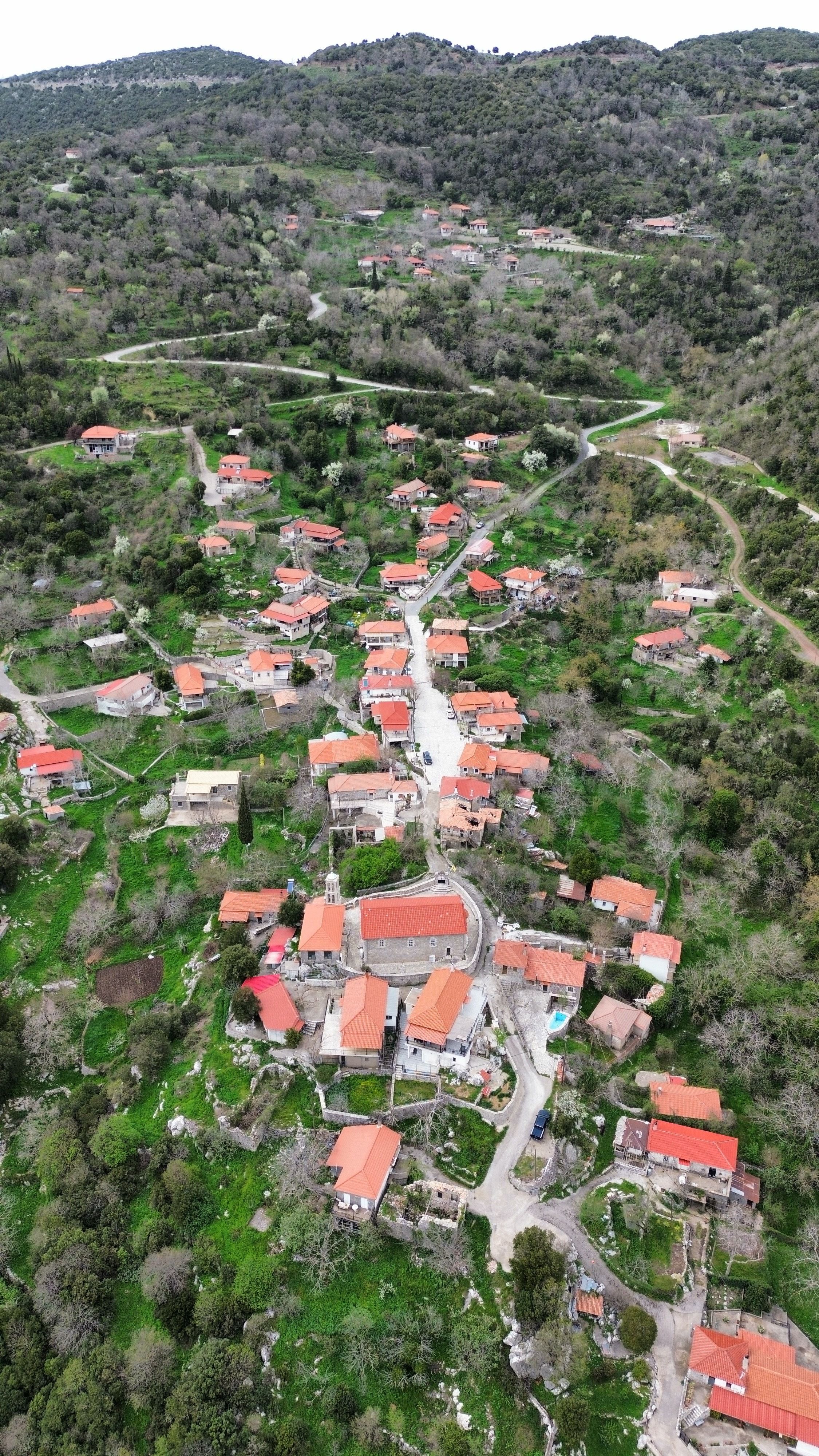 A stunning aerial view captures the scenic beauty of Skliros village with red-roofed houses and lush greenery.