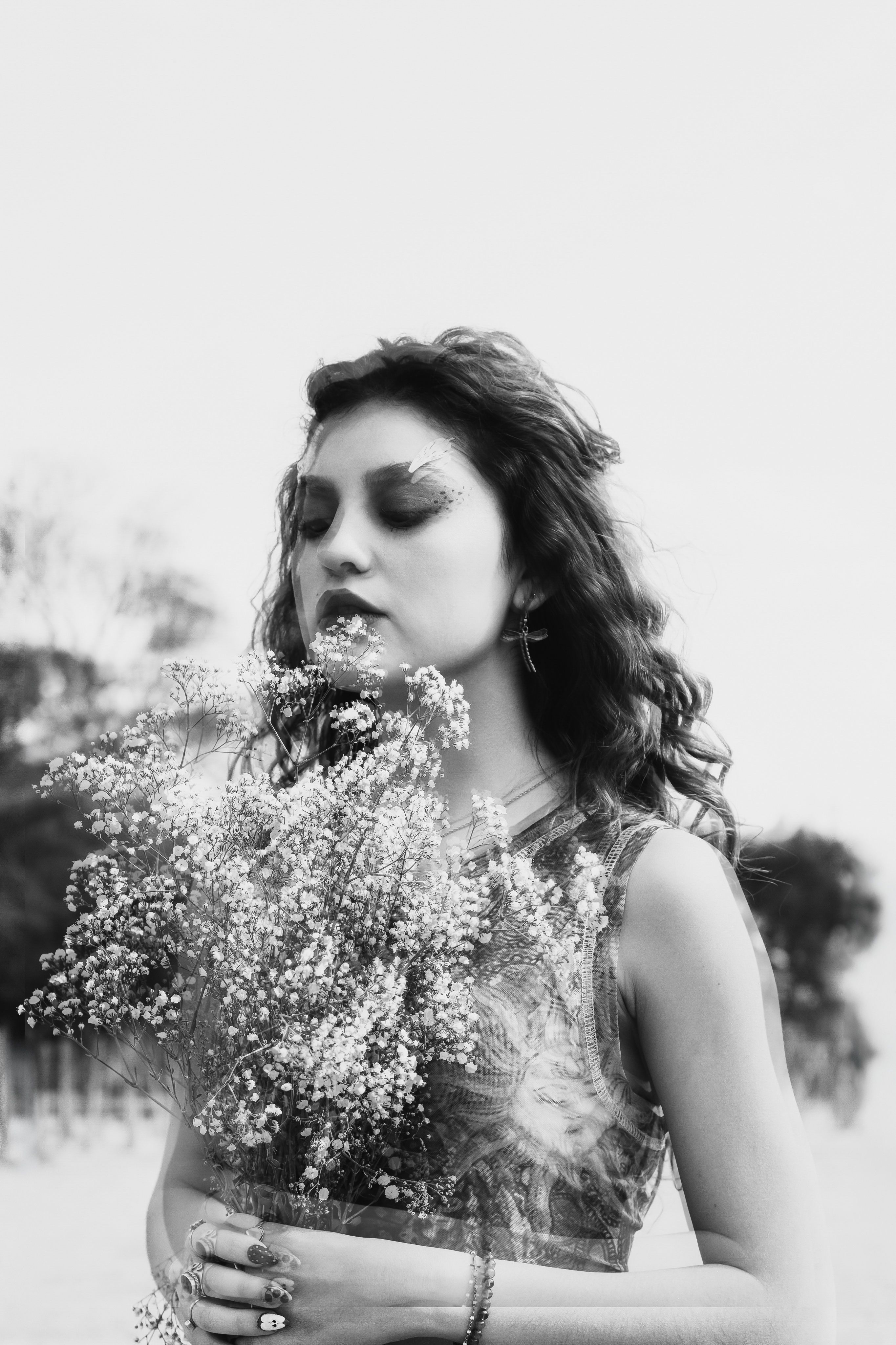 Fotomural Retrato de una mujer contemplativa sosteniendo un ramo de flores al aire libre. Capturada en blanco y negro, transmite una atmósfera tranquila y onírica.