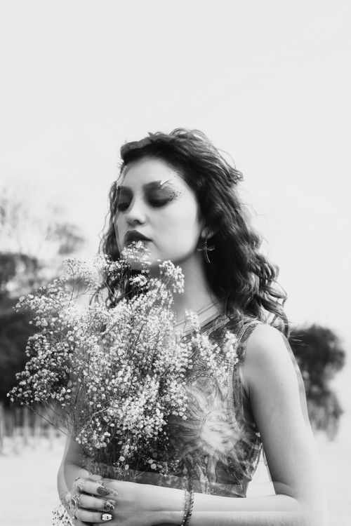 Free Portrait of a contemplative woman holding a bouquet of flowers outdoors. Captured in black and white, exuding a calm and dreamy mood. Stock Photo