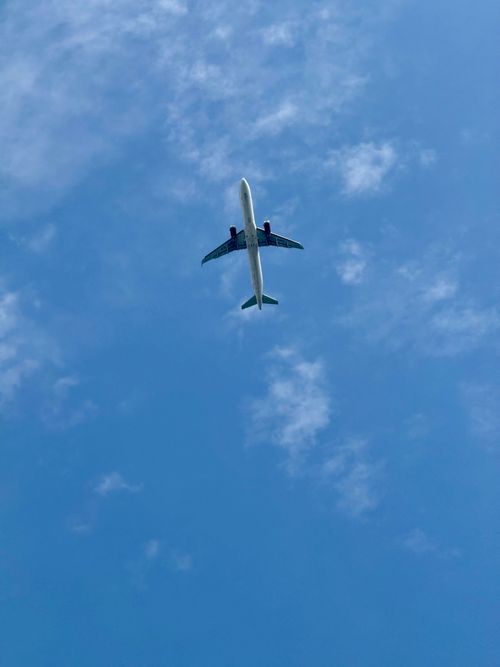 Free Commercial airplane flying high in a clear blue sky with scattered clouds, viewed from below. Stock Photo