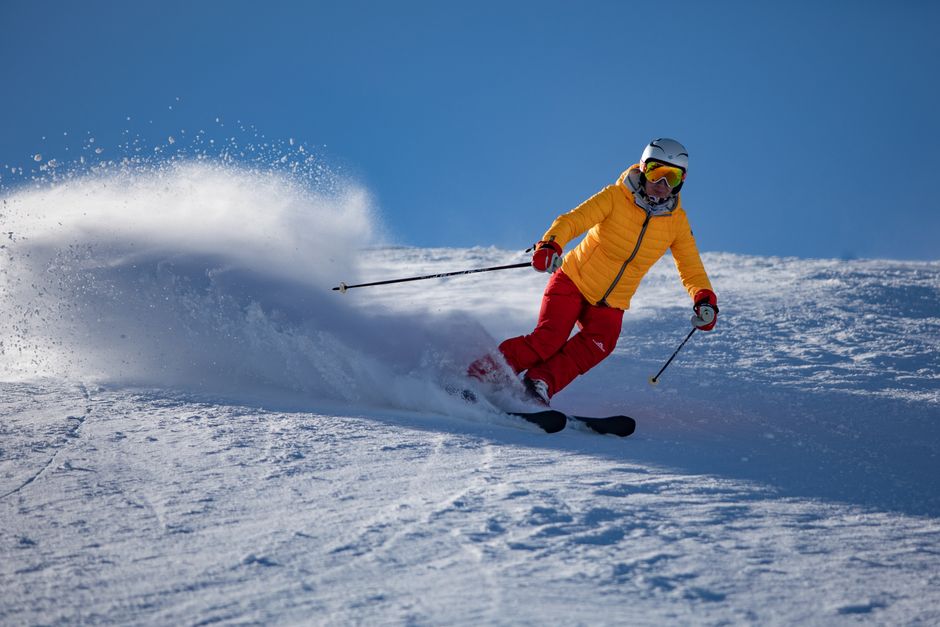 A skier wearing bright gear expertly navigates a snowy slope with speed and precision.