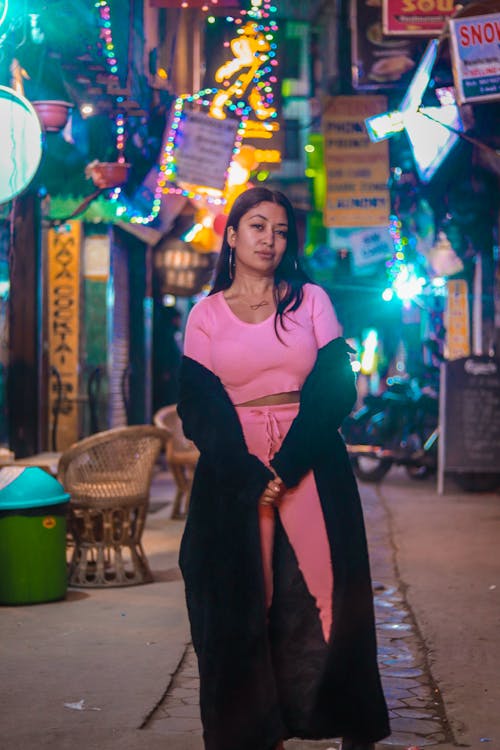 Woman in Pink Dress Standing on Street During Nighttime
