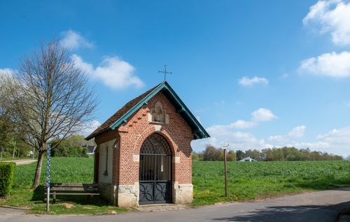 Free A quaint brick chapel stands in Beersel, Belgium under a bright blue sky, surrounded by lush greenery. Stock Photo