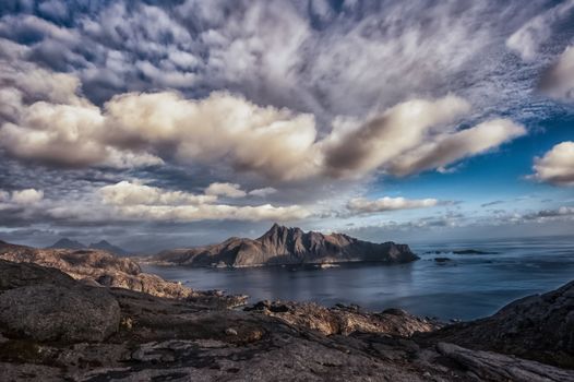 Breathtaking view of the Lofoten Archipelago in Norway under dramatic skies, showcasing rugged mountains and tranquil waters.