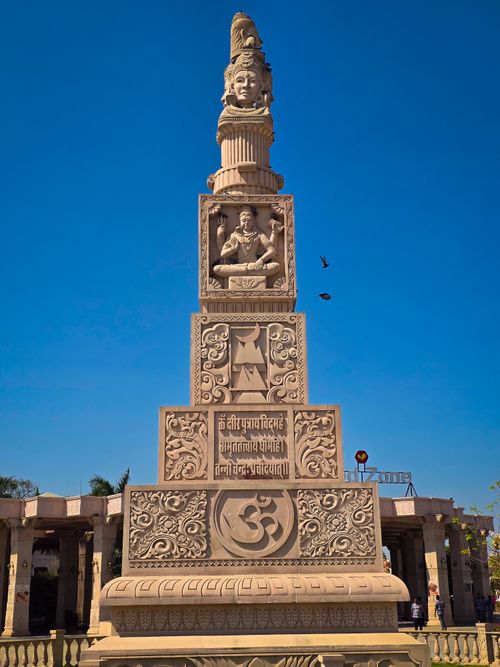 Free A towering intricately carved monument featuring Hindi script and deity carving under a clear blue sky. Stock Photo