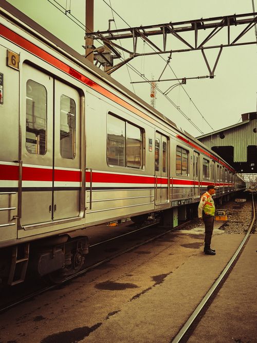 Free Train station scene in West Java, Indonesia, featuring a worker next to a train. Stock Photo