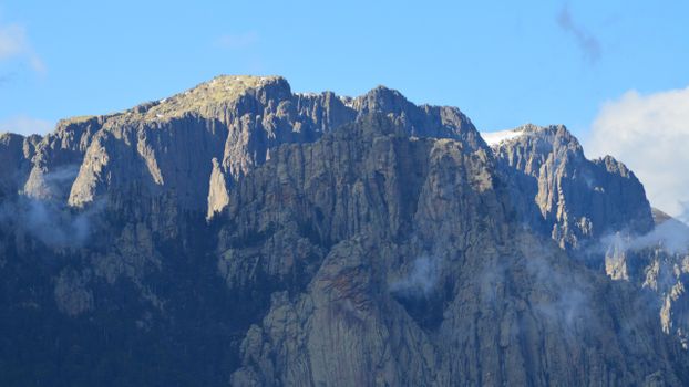 Majestic view of mountain peaks in Zonza, Corsica with mist and clear blue skies.