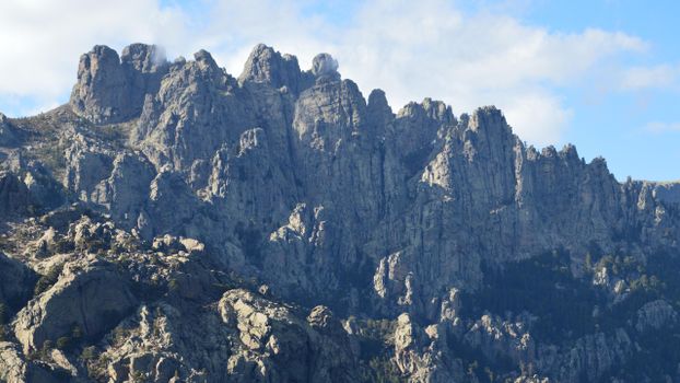 Majestic rocky mountain peaks under a bright blue sky in Zonza, Corsica.