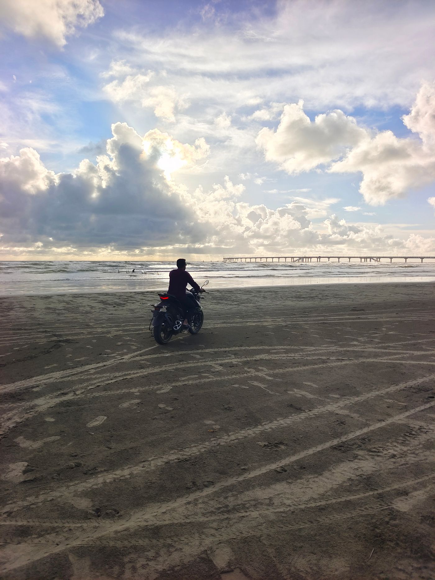 Motociclista viajando de moto no Carnaval em estrada de praia ao pôr do sol