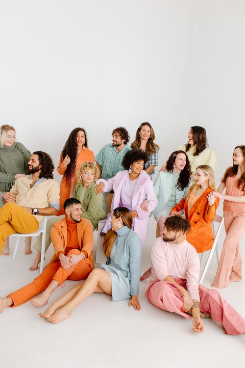 Free Diverse group of adults in vibrant pastel clothing posing happily in a studio. Stock Photo