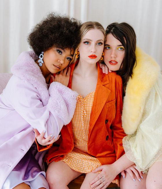 Three women in vibrant outfits embracing fashion and diversity indoors.