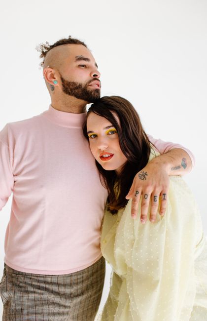 Intimate portrait of a diverse couple embracing in modern fashion with tattoos visible.