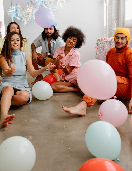 Free A group of diverse young adults enjoying a playful indoor party with colorful balloons. Stock Photo