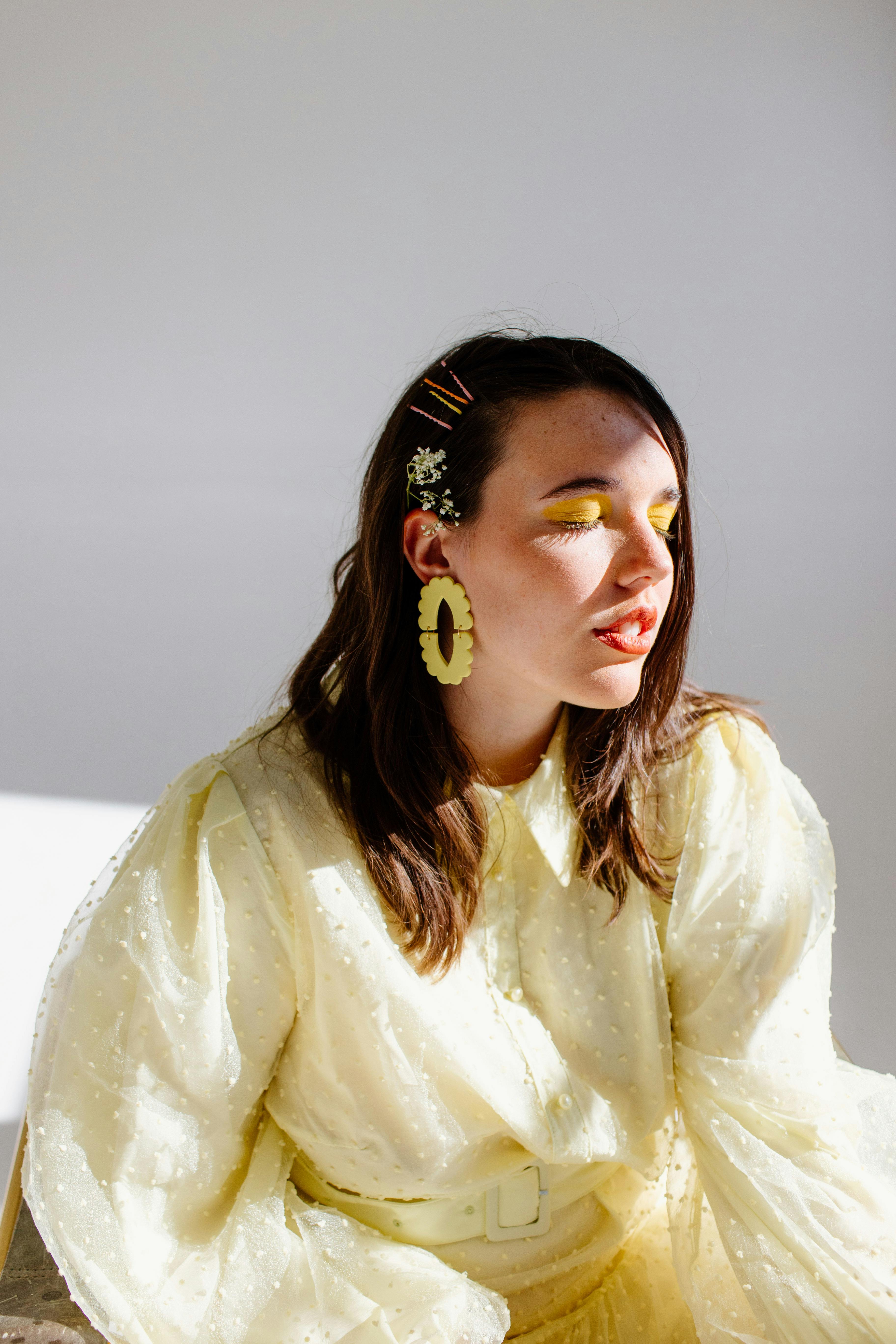 Young woman in a bright yellow outfit enjoying sunlight indoors.