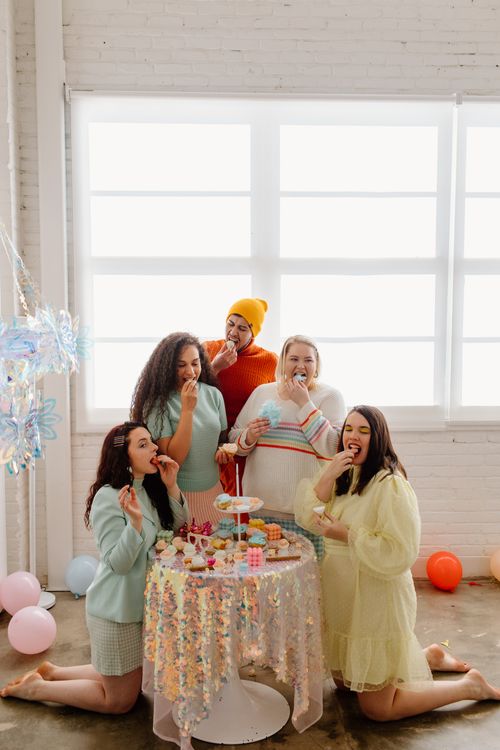 Free A diverse group of friends enjoys a colorful indoor party with sweets and laughter. Stock Photo
