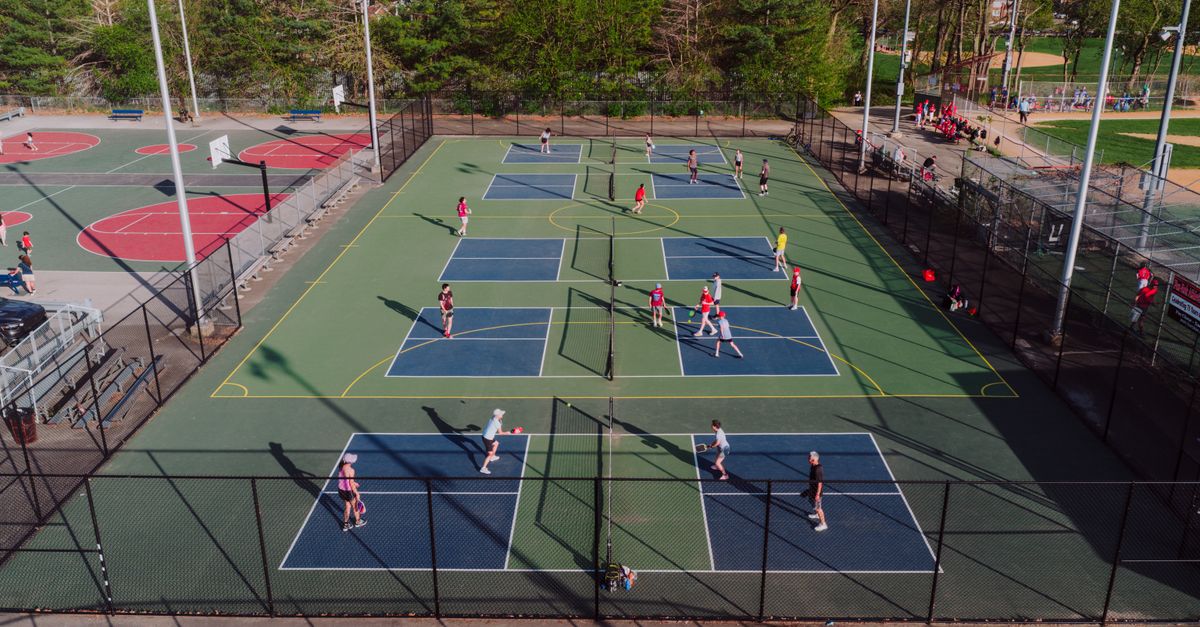 A lively pickleball game at outdoor courts in Philadelphia, captured from above on a sunny day.