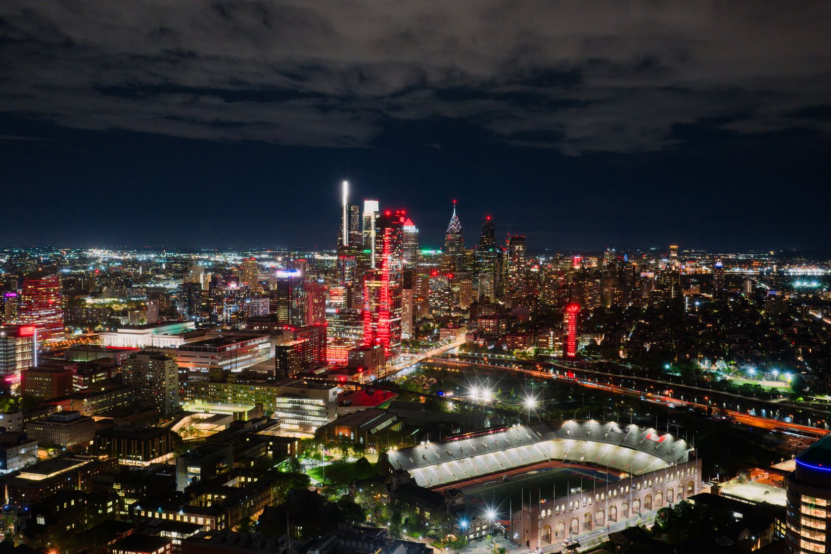 A breathtaking aerial view of Philadelphia's illuminated skyline at night, highlighting the vibrant cityscape and a prom