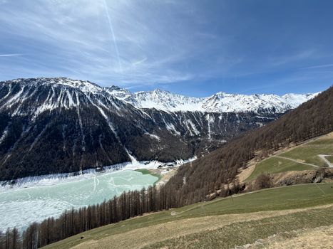 Stunning view of snow-covered alpine mountains and a partially frozen lake in Trentino-Südtirol, Italy.
