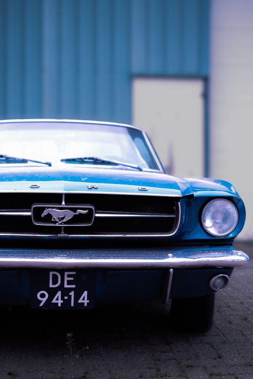 Free Front view of a classic vintage blue car parked outdoors with blurred background. Stock Photo