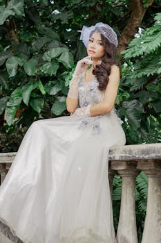 美丽的新娘穿着婚纱，在户外郁郁葱葱的绿色背景下优雅地摆着姿势