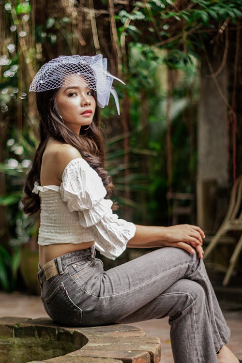 Mulher Com Boné De Malha Branca E Jeans Azul Sentada No Banco De Concreto