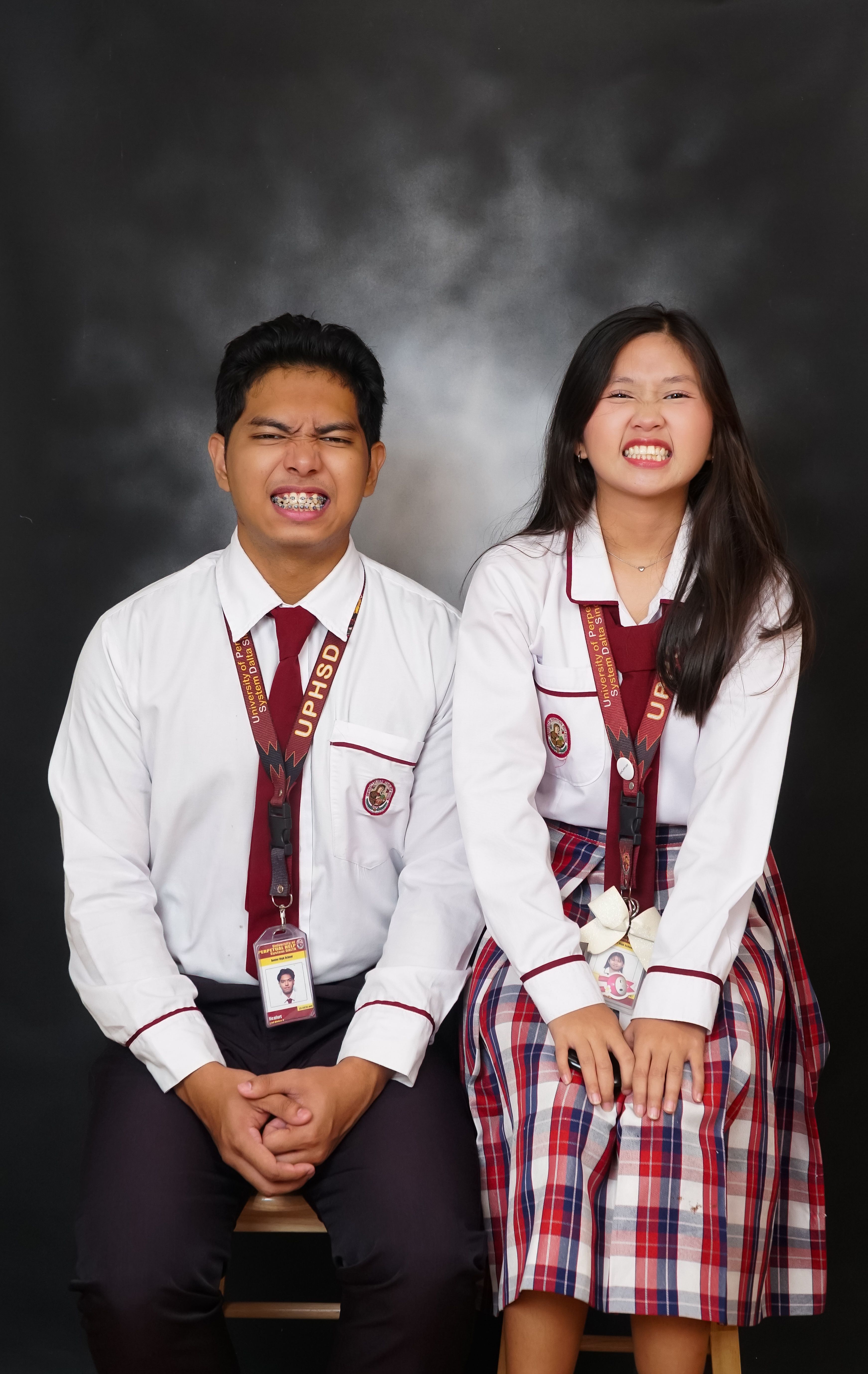 Two students making funny faces in school uniforms. A candid and playful moment.