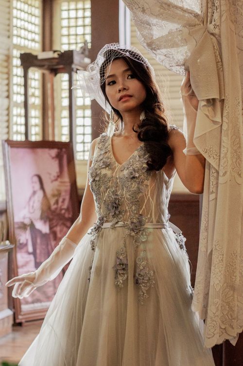 Free Elegant bride wearing a vintage wedding gown indoors, captured with natural lighting. Stock Photo