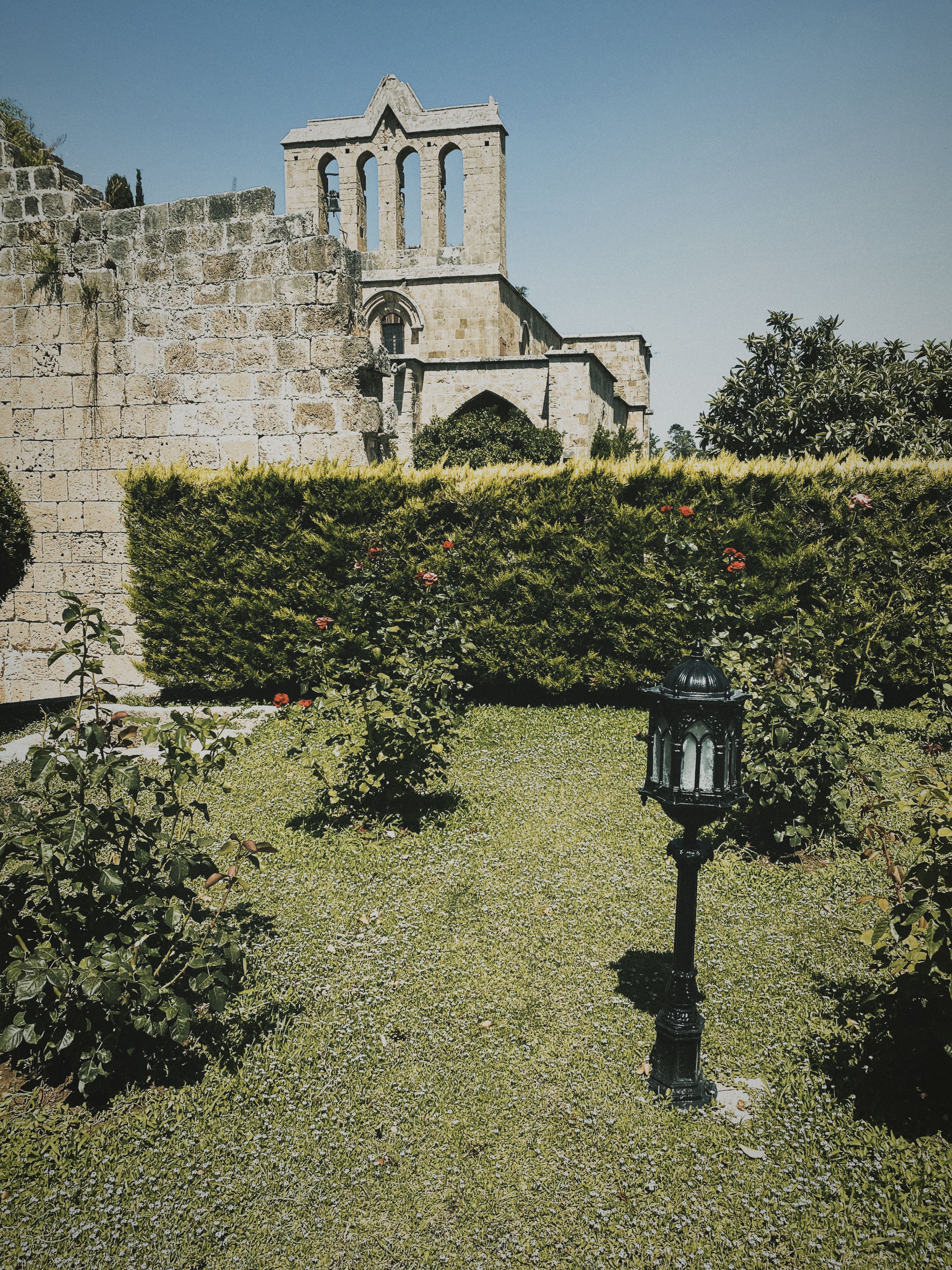 Fotomural Un jardín pacífico con ruinas históricas de la abadía bajo un cielo despejado, ideal para inspiración de viaje.