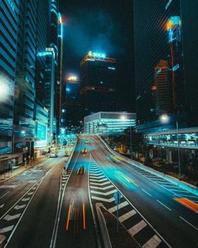 Dynamic city street view at night, showcasing vibrant lights and motion blur in a modern urban environment.
