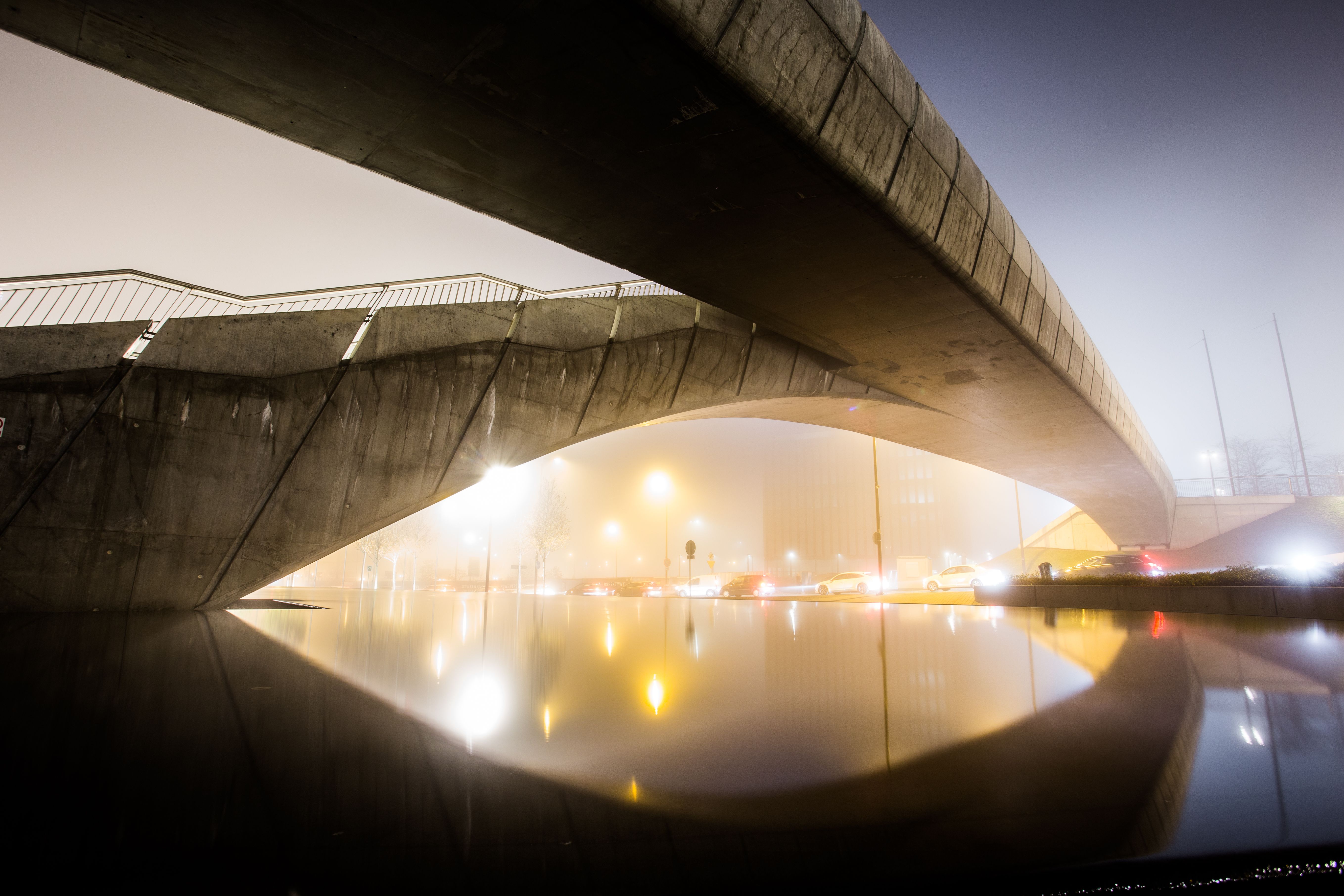 A foggy night view of a modern bridge with a stunning reflection in Katowice, Poland.