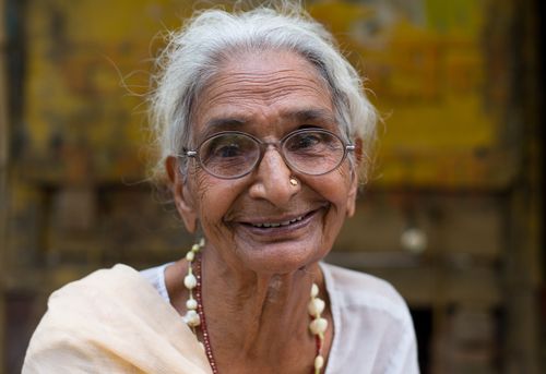 Free A joyful elderly woman with glasses smiling warmly in an outdoor setting. Stock Photo