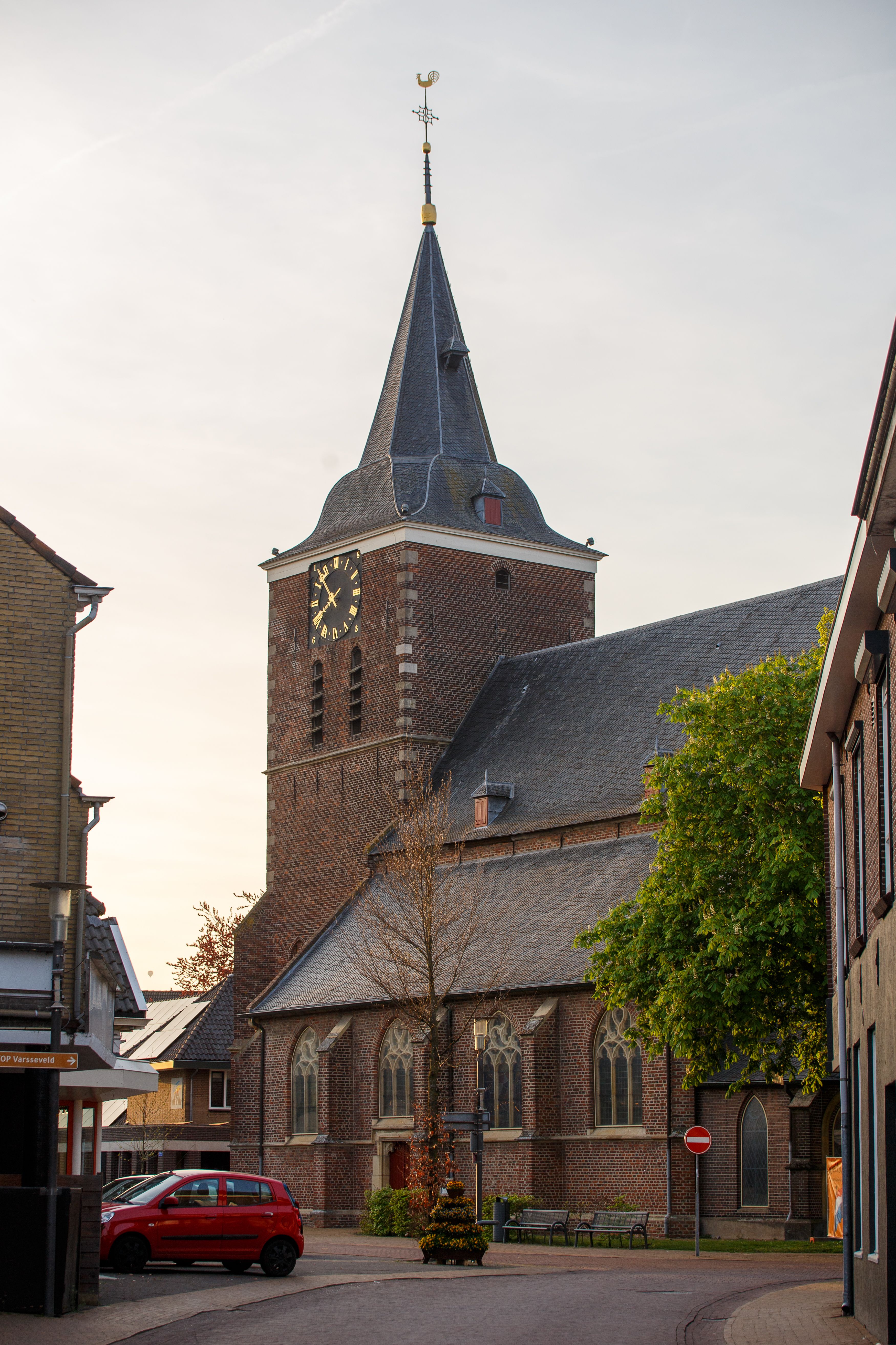Charming view of a historic church tower in a Dutch village, captured at sunset.