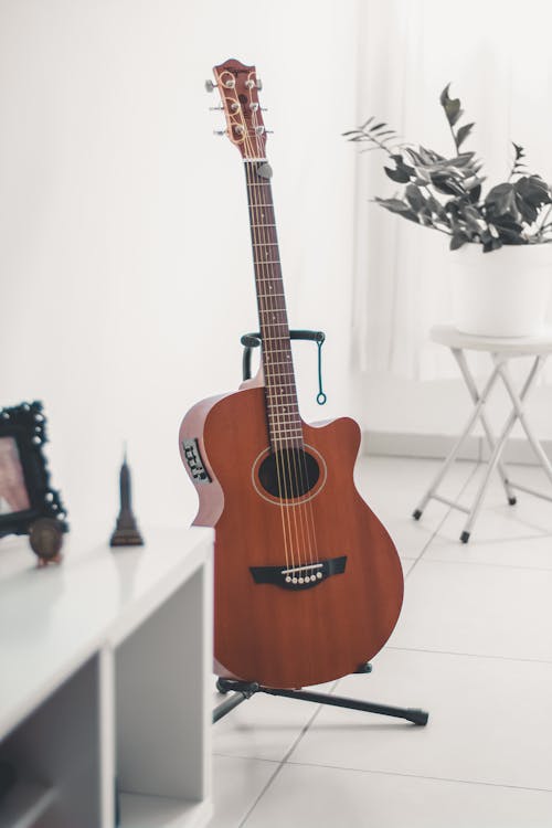 Free Brown Acoustic Guitar on Black Guitar Stand Stock Photo