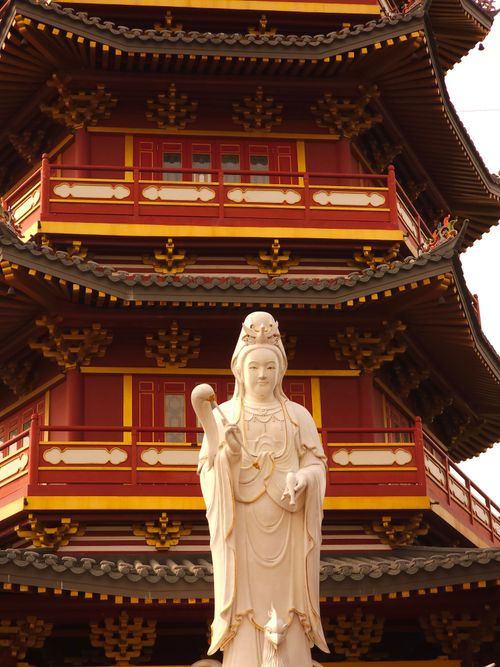Free A serene statue in front of a beautifully detailed traditional Chinese pagoda. Stock Photo