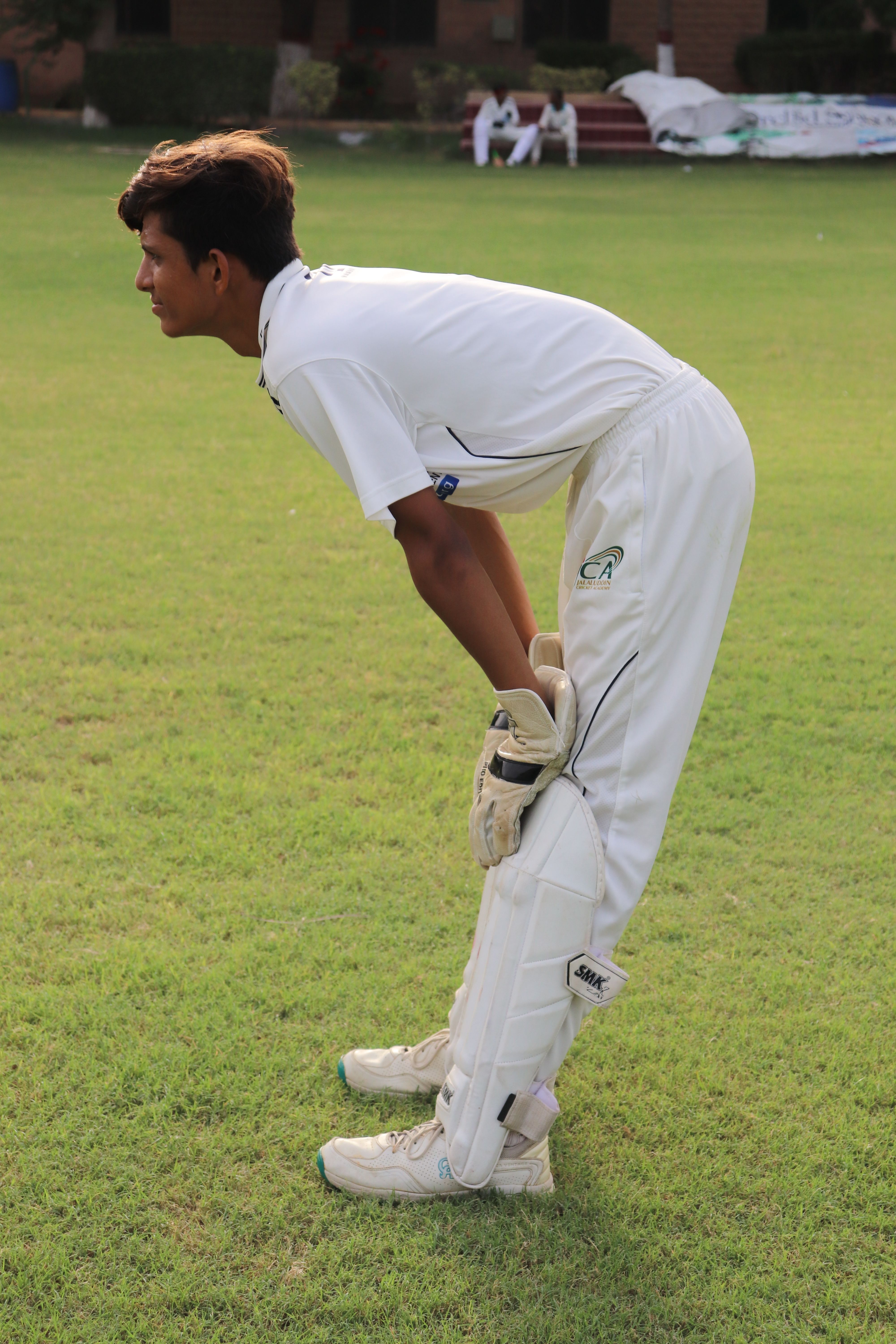 Young cricket player in action on a sunny day at a cricket ground in Pakistan.